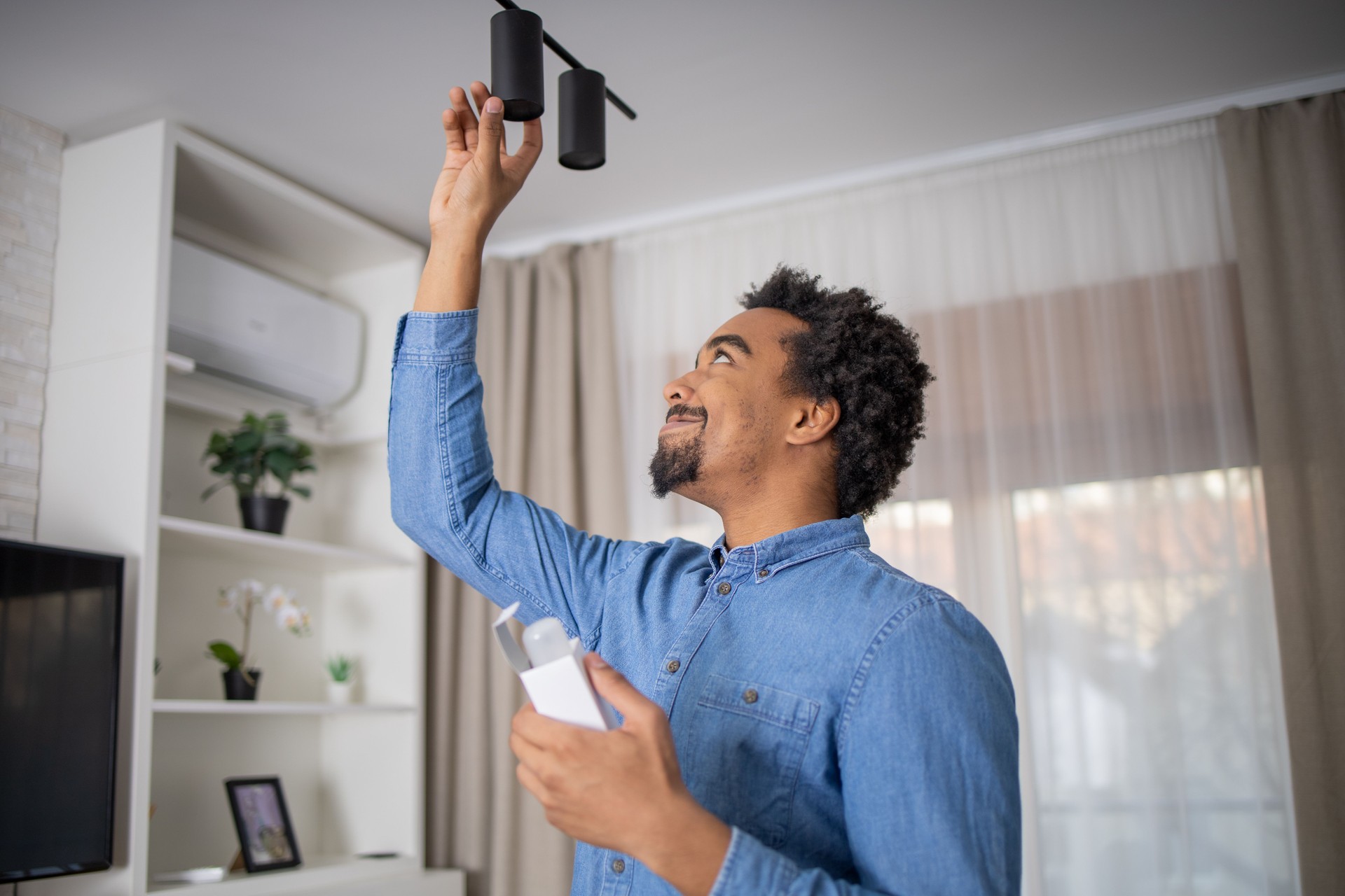 Young man is changing a light bulb