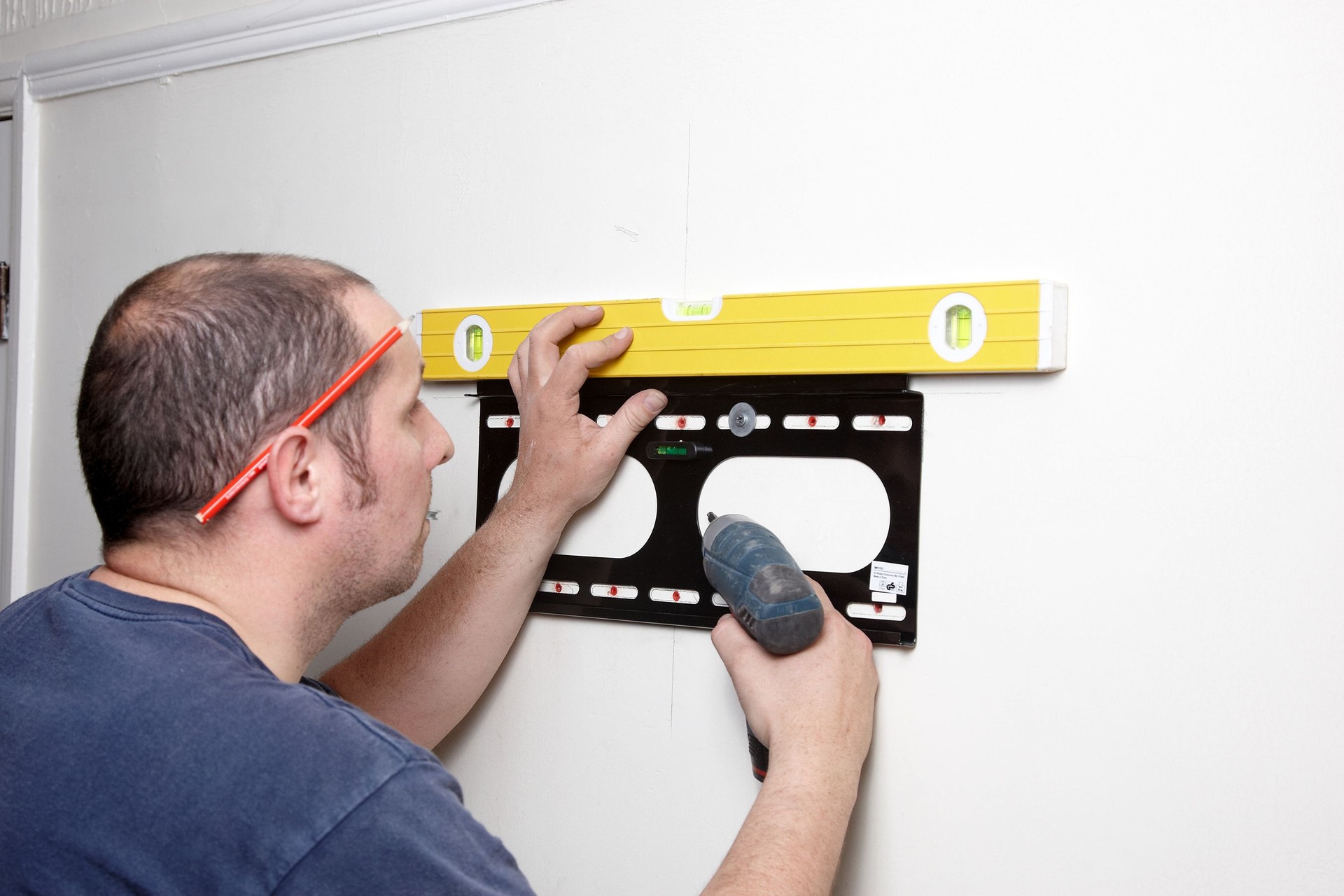 Electrician fitting TV bracket to wall