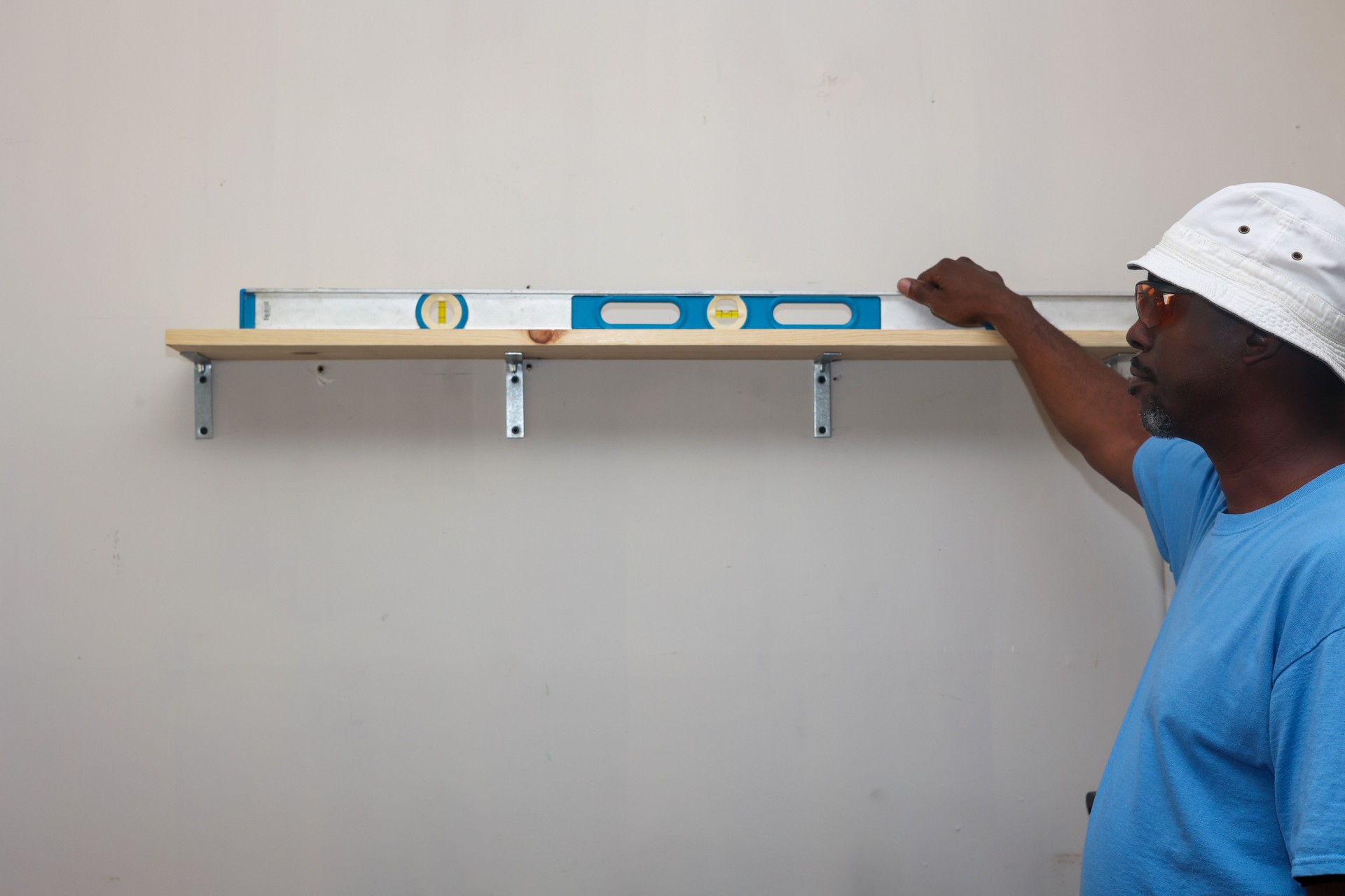 Portrait of a black man holding a spirit level against a white wall